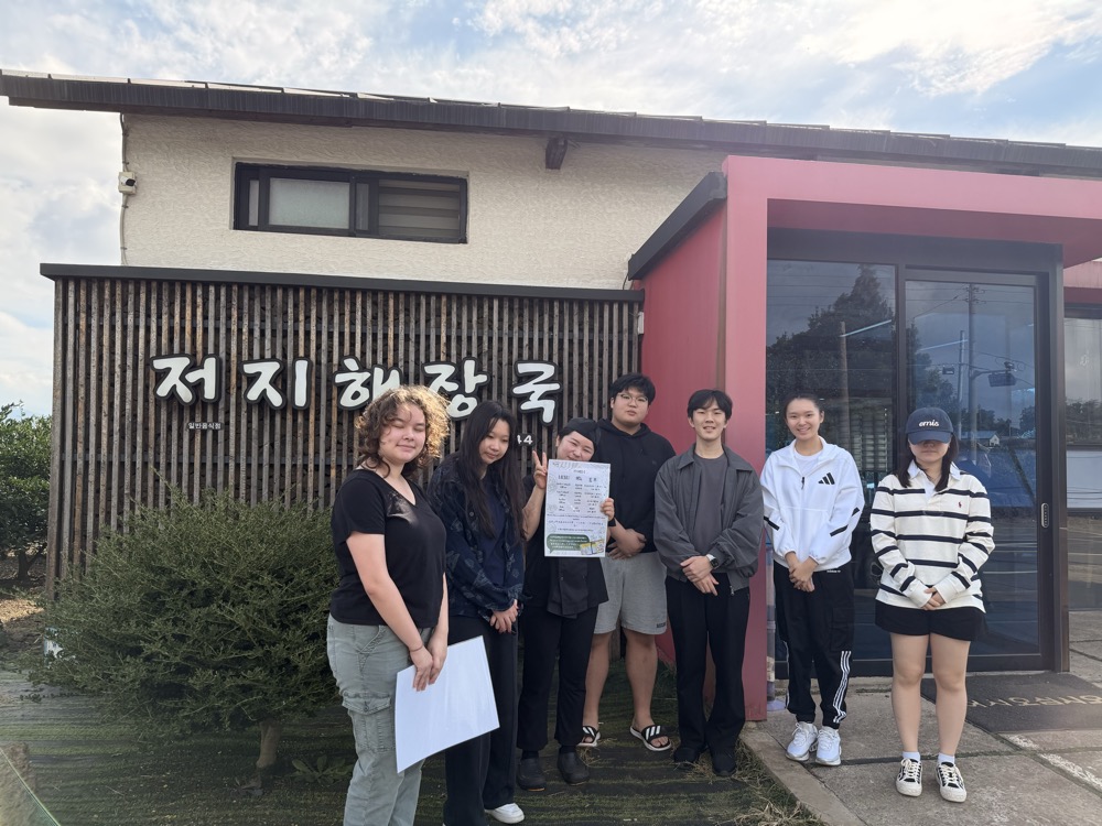 Students and the owner of Jeoji Haejangguk holding the new menu sheet outside the restaurant